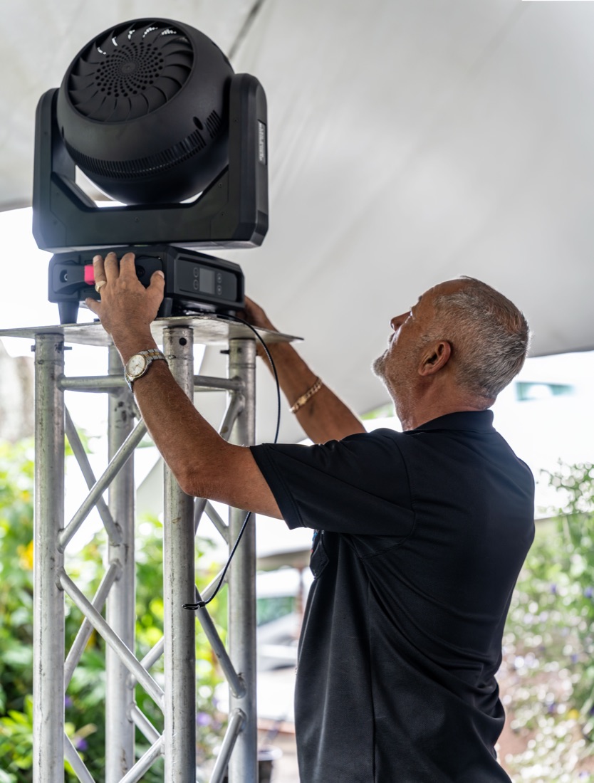 Jorge Bolaños, fundador de Eventos Tío, instalando una cabeza móvil sobre una torre de truss